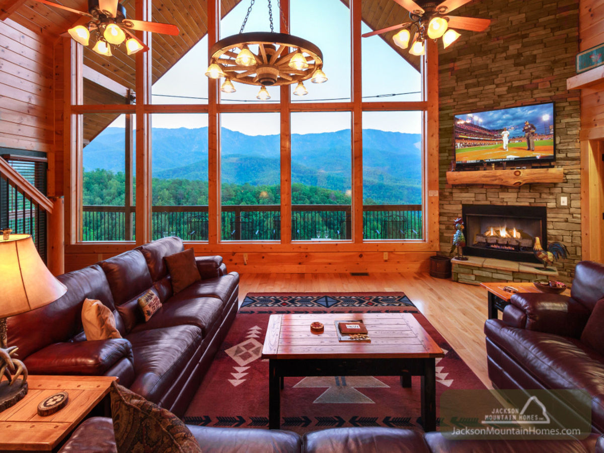 The rustic living room of this Smoky Mountain cabin offers sumptuous leather couches and stunning views of rolling blue mountains.